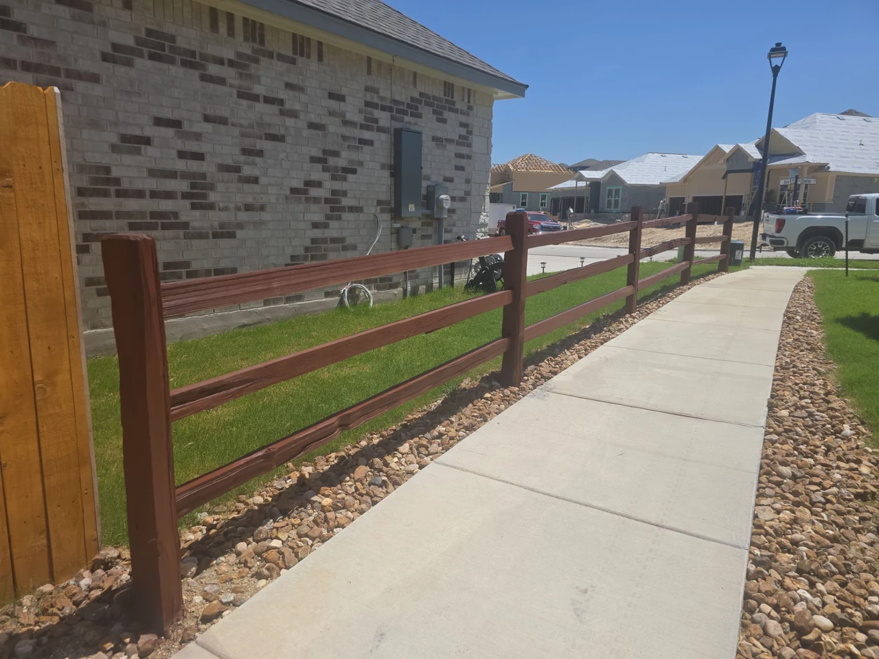 The same wood rail fence after staining beside the community walkway.