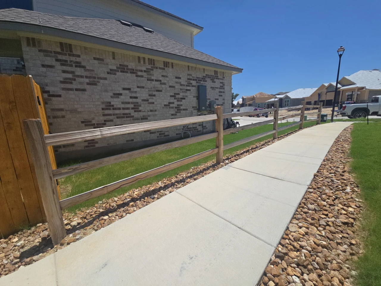 Wood rail fence before staining beside a community walkway.